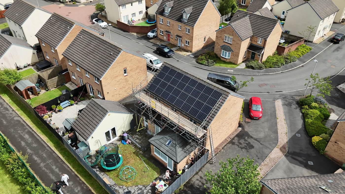 Drone photo of a full-roof solar array on a new-build semi, scaffold still up on install day